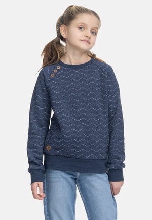Felpa blu navy con motivo a zigzag e dettagli in legno. Presenta polsini e orlo a coste. Abbinata a jeans azzurri.