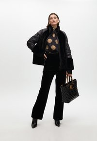 Black faux fur and quilted jacket, gold polka dot top, black velvet wide-leg pants, pointed toe boots, and a black quilted handbag with gold accents.