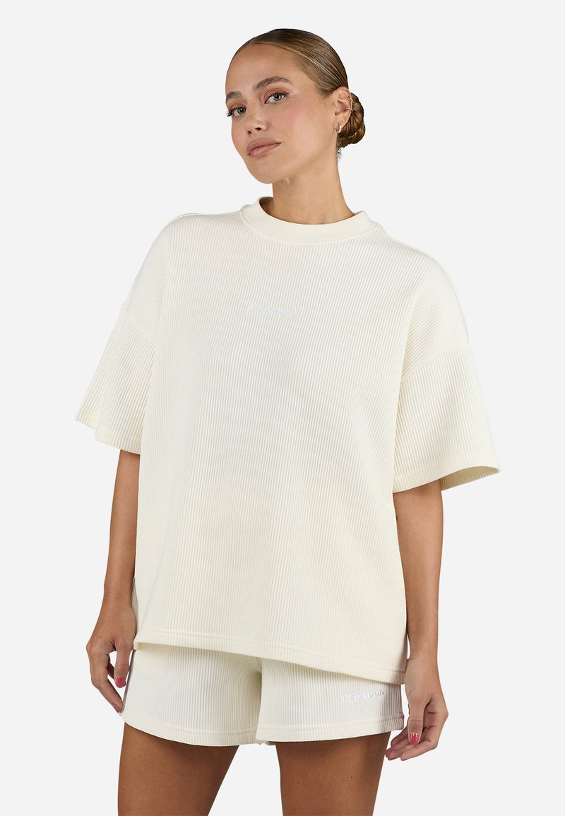 T-shirt oversize a coste crema con maniche corte e collo a giro, abbinato a pantaloni corti coordinati con un piccolo logo.