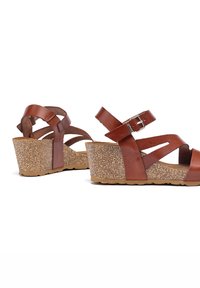 Sandali wedge in pelle marrone con fasce incrociate, piattaforma in sughero texturizzato e dettaglio con fibbia. Suola in gomma flessibile per il comfort.
