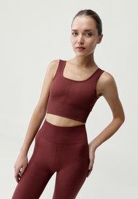 Bordový rebrovaný crop top a legíny s vysokým pásom. Tkanina má textúrovaný povrch s priliehavým strihom a širokými ramienkami.