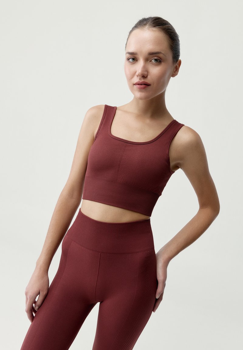 Bordový rebrovaný crop top a legíny s vysokým pásom. Tkanina má textúrovaný povrch s priliehavým strihom a širokými ramienkami.