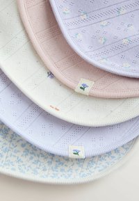 Stoh pastelovo sfarbených dojčenských podbradníkov s textúrovanými pletenými vzormi a malými kvetinovými potlačami na látkových štítkoch, usporiadaných na bielom povrchu.