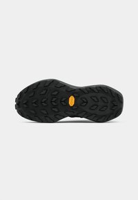 Black athletic shoe outsole with aggressive tread pattern, featuring a Vibram logo in yellow and textured surfaces for traction.