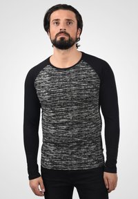 Svart og grå langermet skjorte med et teksturert, stripete mønster på kroppen og ensfargede svarte ermer, rund halslinning.