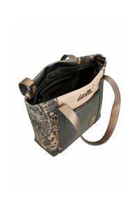 Schwarze und beige Tote Bag mit Camouflage-Muster; Außenmaterial aus Kunstleder; Reißverschluss oben; verstellbarer Schultergurt; sichtbare Innentaschen.