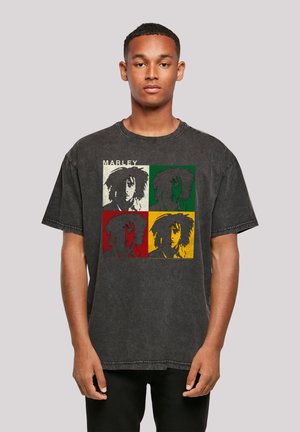 Black graphic oversized t-shirt featuring a four-panel print of a person's face in green, red, yellow, and beige. Round neck design, short sleeves.