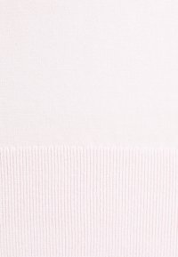 Ljust rosa stickad tyg med fin struktur, med en ribbad fåll i nederkant. Enhetlig färg med jämn yta genomgående.