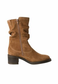 Bottine en daim marron avec une tige texturée, fermeture éclair sur le côté, design ample et talon empilé. Coutures accentuées sur les côtés.