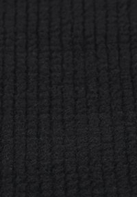 Svart texturerat tyg med vertikal ribbstruktur, tillverkat av mjukt material som ger ett mysigt och varmt utseende. Idealiskt för klädsel eller plagg.