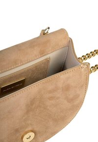 Beżowa torebka z zamszu z zamknięciem w złotym kolorze. Posiada łańcuszkowy pasek oraz miękkie wnętrze z miejscami na karty. Okrągły kształt.