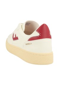 Sneaker in pelle bianca con tallone rosso e dettagli del logo, suola testurizzata e cuciture a contrasto. Presenta una suola in gomma color cuoio.
