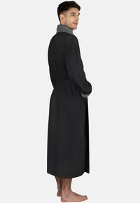 Schwarzer, strukturierter Morgenmantel mit einem grauen Kragen, der einen taillierten Schnitt und dezente weiße Nähte entlang der Kragenkante aufweist. Bodentiefe Ausführung.