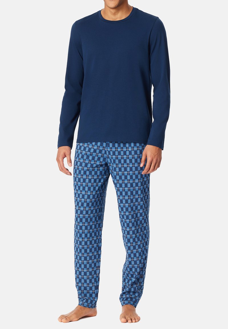 Marineblauwe longsleeve top met ronde hals, gecombineerd met gestreepte blauwe pyjamabroek met een ruitpatroon in donkere en lichte tinten.