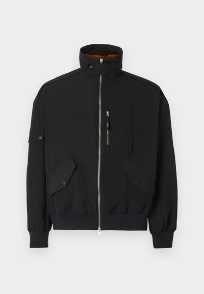 Kerge kanga eest must jope, millel on kõrge krae, tõmblukuga esi, rinna tasku ja kaks esist flap-taskut, millel on kinnituskohad.