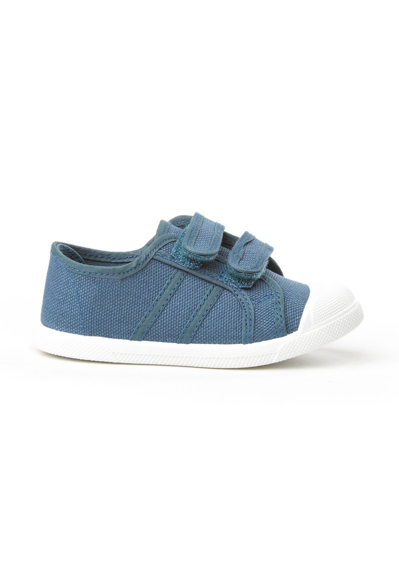 Zapatilla azul para niño pequeño con dos correas de velcro y suela y puntera de goma blanca sobre un fondo blanco.
