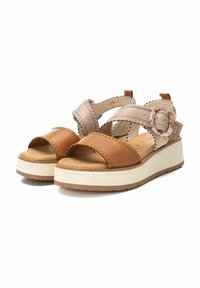 Sandalias de cuero marrón y beige con suela de plataforma, que presentan tiras cruzadas, hebilla circular y costura decorativa a lo largo de los bordes.