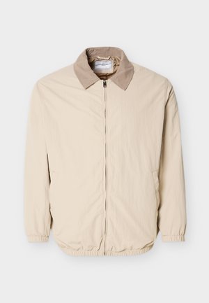 Beige Leichtjacke mit einem etwas dunkleren Kragen, vorderem Reißverschluss, elastischen Ärmelabschlüssen und zwei Seitentaschen.