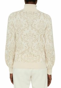 Stickad krämfärgad tröja med en subtil beige damaskmönster, hög krage och ribbade ärmslut och nedkant, med en mjuk struktur och avslappnad passform.