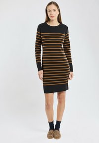 Robe noire avec des rayures horizontales orange, manches longues et encolure ras du cou. Le tissu semble doux avec une silhouette ajustée.