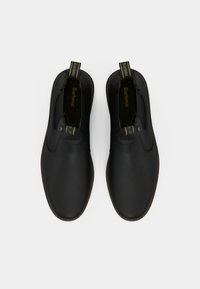 Par de botins pretos de tornozeleira, sem atacadores, com puxadores que exibem o logótipo "Barbour", apresentados de cima para baixo sobre um fundo branco.