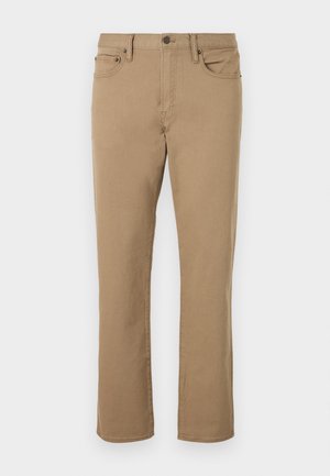 Pantalon beige à jambes droites avec bouton frontal, fermeture éclair, passants de ceinture et design à cinq poches sur fond blanc.