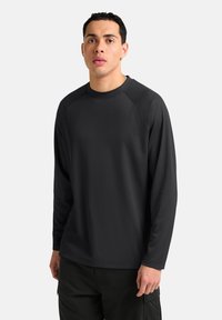 Langsleeve shirt in effen zwart, gemaakt van zachte stof met een ronde halslijn en raglanmouwen, met een relaxte pasvorm en minimale details.