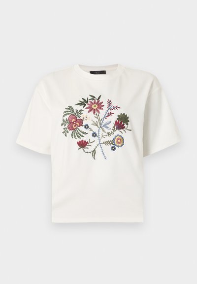 Λευκό κοντομάνικο μπλουζάκι με πολύχρωμο κεντητό σχέδιο λουλουδιών στο κέντρο του στήθους σε απλό φόντο.