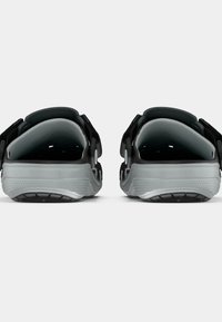 Czarne sandały z odkrytymi piętami i teksturowaną szarą podeszwą, wyposażone w regulowane paski, zaokrąglony kształt oraz otwory wentylacyjne zapewniające oddychalność.