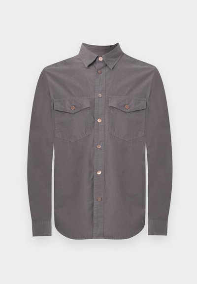 Γκρι πουκάμισο με μακριά μανίκια, κουμπιά, μυτερό γιακά και δύο εμπρόσθιες τσέπες με καπάκι, καθεμία ασφαλισμένη με ένα κουμπί.