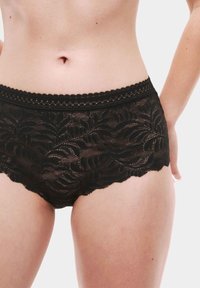 Perizoma nero in pizzo con motivo floreale, bordi scallop e una cintura elastica decorativa. Tessuto leggero e semi-trasparente.