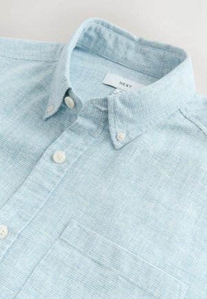 Világoskék hosszú ujjú ing texturált mintával, gombos gallérral és mellzsebbel. Fehér gombokkal és finom szövésmintával rendelkezik.