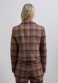 Brown and tan plaid blazer with a tailored fit, featuring a notched collar and two back vents. Textured fabric with contrasting blue lines.