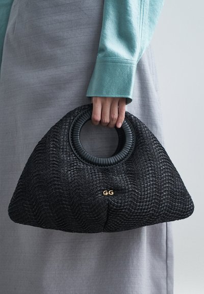 Sac à main noir tressé avec une surface texturée, anse circulaire noire et accent en or avec le logo GG à l'avant.