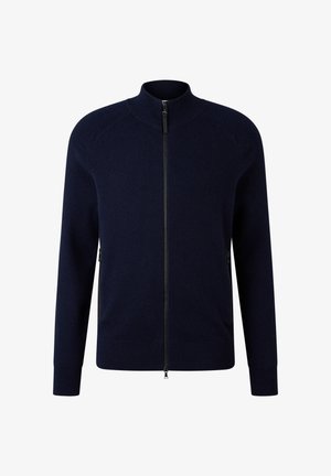 Marineblauwe trui met rits en hoge kraag, geribbelde textuur op schouders en manchetten, en zijzakken, gemaakt van een zachte, warme stof.