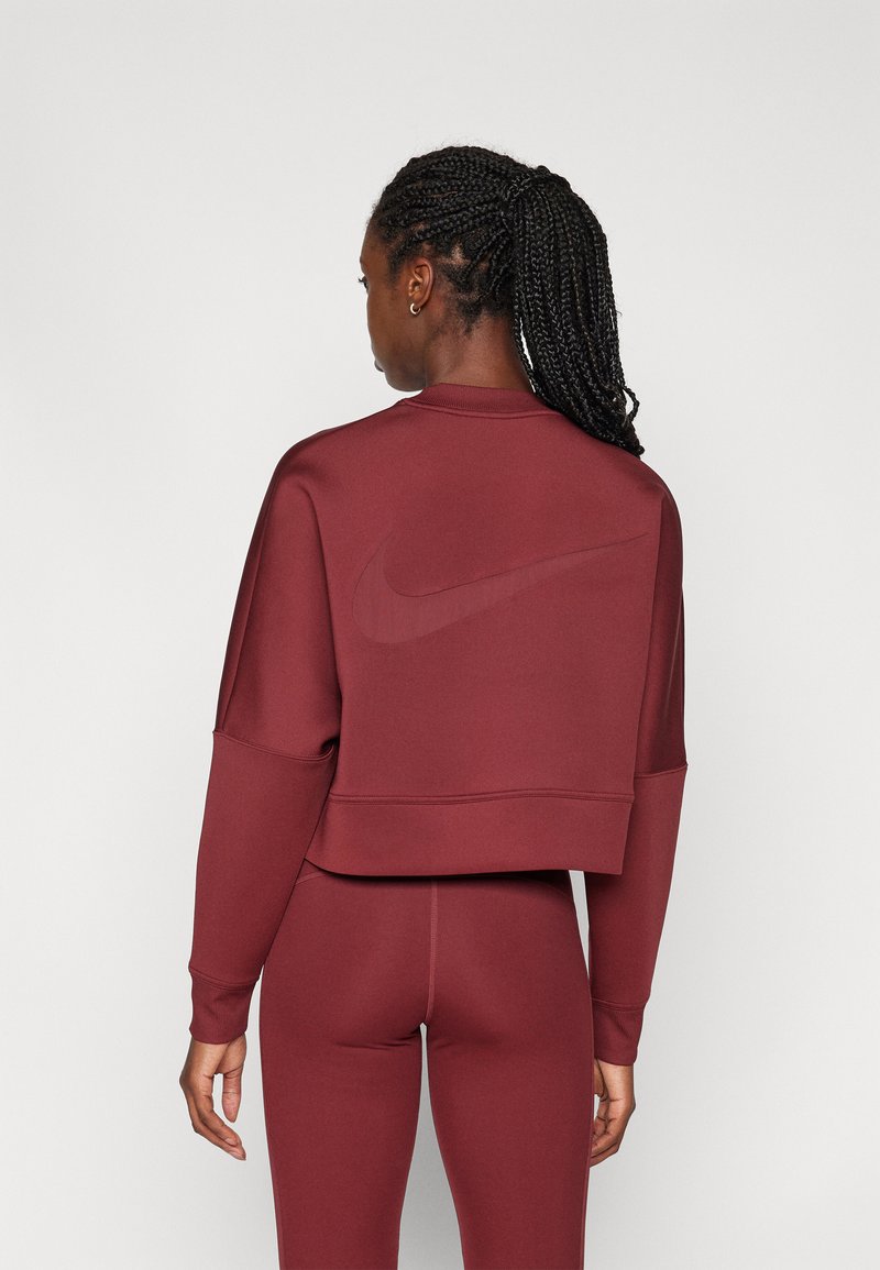 Felpa corta bordeaux con maniche lunghe, caratterizzata da un logo in rilievo discreto sulla schiena, abbinata a leggings coordinati. Texture liscia.