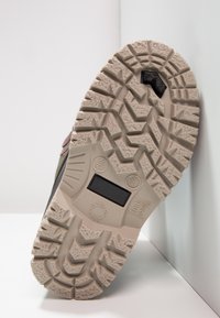 Gumowa podeszwa z głębokim bieżnikiem, wyposażona w czarny wstawka oraz oznaczenia rozmiaru i informacji produkcyjnych. Kolor jasnobeżowy.