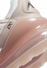 Sneakers med ett ljusbeige mesh-överdela, genomskinlig rosa luftdämpning och svarta logotyp-accenter. Har en slät yta och rund form.
