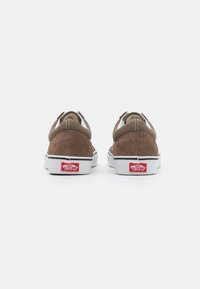 Bruna mockasinlowsneakers med vita gummisulor. Har en vadderad krage, kontrasterande sömmar och röd Vans-logga på hälen.