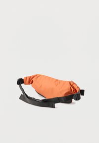 Πορτοκαλί υφασμάτινη τσάντα μέσης με μαύρο ρυθμιζόμενο ιμάντα και αγκράφα πλευρικής απελευθέρωσης, απεικονίζεται πάνω σε απλό ανοιχτό φόντο.