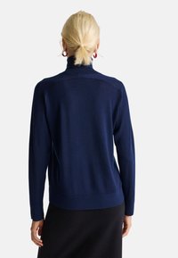 Maglione blu navy con colletto alto, maniche lunghe e orlo a coste. Realizzato in materiale morbido, presenta una texture liscia e un design aderente.