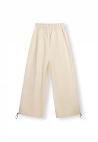 Pantaloni larghi color beige chiaro realizzati in un tessuto morbido. Presentano un elastico in vita e dettagli con coulisse all'orlo.