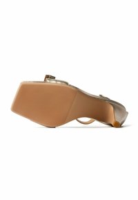 Damengoldene offene Zehen Slingback Absatzschuh, von der strukturierten Sohle mit niedrigem Kitten-Heel auf weißem Hintergrund gezeigt.