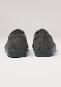 Chaussures en daim gris avec une silhouette basse, surface texturée et semelles en caoutchouc. Présente un détail de couture subtil et une languette à l'arrière.