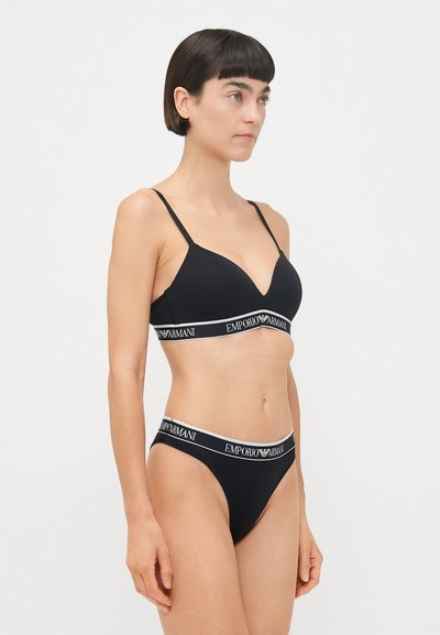 Zwarte katoenen beha en string set met een V-hals ontwerp, dunne bandjes en een elastische band met het Emporio Armani-logo. Glad textuur.