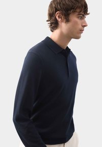 Marineblaues Langarm-Polohemd aus weichem Stoff, mit klassischem Kragen, Knopfleiste und taillierter Passform mit glatter Oberfläche.