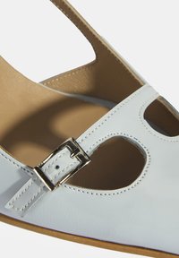 Weiße Leder-Sandale mit einem Ausschnitt-Design, Schnallen-Detail und glatter Textur. Tan-Fußbett mit kontrastierenden Nähten.