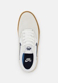 Baskets en daim blanc avec accents bleu marine, semelle en caoutchouc et lacets blancs. Dotées d'une semelle intérieure rembourrée avec le logo "NIKE SB" sur la languette.