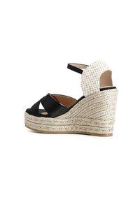 Wedge espadrilles nere con una piattaforma in juta intrecciata, caratterizzate da un design a strisce incrociate e una parte posteriore bianca testurizzata.