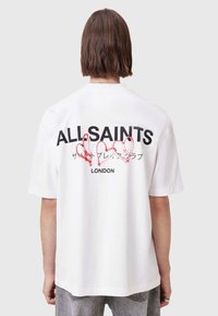 Hvit bomulls t-skjorte med store svarte bokstaver "ALLSAINTS" og røde hjerteomriss på baksiden, med en avslappet passform og korte ermer.